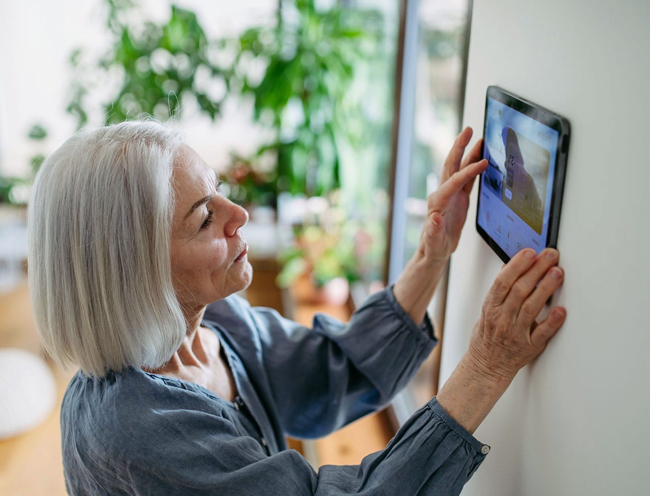 Woman using a touchpad for easy home automation in Florida by Definitive Electronics Woman using a touchpad for easy home automation in Florida by Definitive Electronics